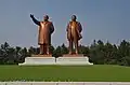 3/4 Statues of Kim Il-sung and Kim Jong-Il (tourism=artwork and artwork_type=statue) in bronze on their square base seen from the ground.