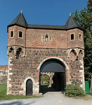 Wicket gate (small door on the left) next to large main gate in a historic castle wall.
