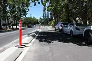 This frontage lane along an urban street in California is separated from the main lane by a curb and rejoins the main lanes at every intersection. highway=service side_road=yes
