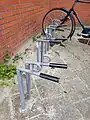 An example of a common type of front-wheel-only bike stand in the Netherlands. No danger of wheel bending, with a loop for attaching a lock.