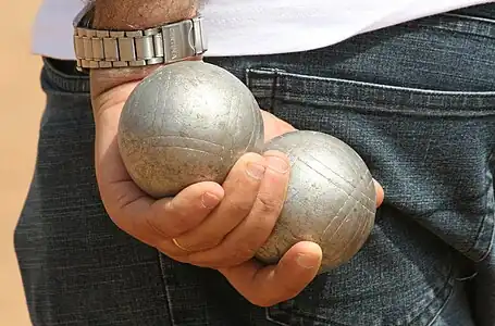 Two boules being held in one hand behind the Pétanque player's back.