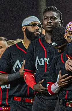 Didi Gregorius, facing forward, and several teammates in dark colored Arabia Wolves jerseys standing in a row