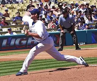 Derek Lowe pitching in a white Los Angeles Dogers uniform, with the third base umpire looking on from behind