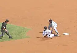 Curtis Granderson sliding into second base, while Yuniesky Betancourt attempts to tag him and umpire Rob Drake looks on from the far left.