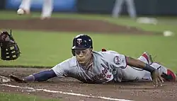 Jorge Polanco sliding and reaching his right hand back to first base, with a disembodied first baseman's mitt on the left and blurring ball likely moving toward the mitt