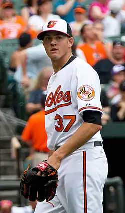 Kevin Gausman in a white Orioles jersey, wearing a glove and looking forward
