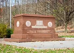 A brick tomb of Jim Thorpe inscribed with depictions of his career and the quote from King Gustav V