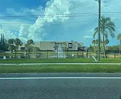 Viewed from the road, a cream-colored midcentury building with a large black sign bearing the WTSP logo