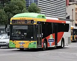 Photo of a single decker bus in a green, red, yellow and white livery