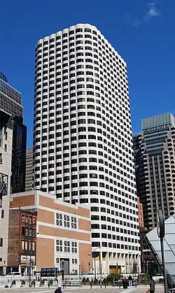 Ground-level view of a building with rounded corners, a grooved, white facade and dark black windows