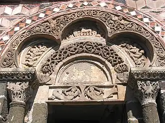 The carving of the polychrome porch of the Saint-Michel-D'aiguilhe chapel, the Aiguilhe, Haute-Loire, France, (11th century), has paired mermaids, and the Lamb of God