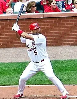 A man with feet spread apart holding a baseball bat in the air
