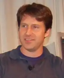 An approximately 38-year-old man looking at something to the left of the camera.