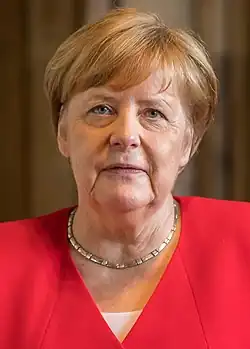 Head shot of Merkel, 64, wearing a necklace and a red blazer, and facing upwards from the camera.