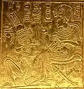 Scene from the golden shrine of Tutankhamun. King and Queen are seated and Tutankhamun seems to pour ointment on Queen's hand.
