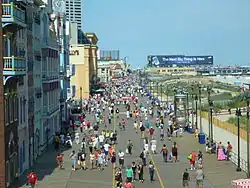 People walking along a wide pathway near the ocean on a sunny day