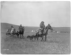 Gros Ventre (Atsina) American Indians moving camps with travois for transporting skin lodges and belongings.