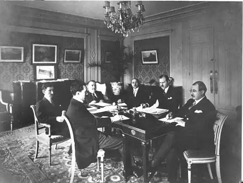 Azerbaijani delegation in Paris at the Claridge Hotel during the Paris Peace Conference, 1919. The tricolor flag of the ADR is visible in the background, on the chest of drawers.