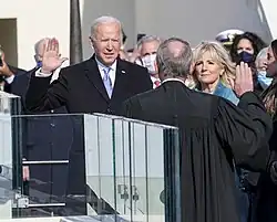 Photo of Biden raising his right hand, with his left hand placed on a thick Bible