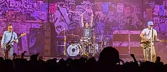 Blink-182 performing in Palm Desert in 2025. Left to right: Mark Hoppus, Travis Barker, and Tom DeLonge.