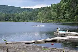 A lake and dock with a boat drifting in the water.