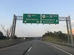 Two lanes of a four-lane highway, with two overhead signs