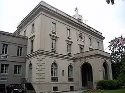 A three-story gray mansion, with a covered front entrance