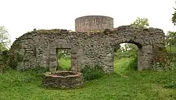 Photo of ruined stone walls and a circular tower in a meadow