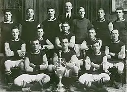 A black and white picture of Burnley posing behind a football trophy