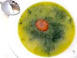 a bowl of green coloured soup with light-coloured vegetables