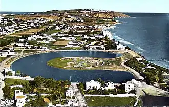 a colour photograph of a semi-urban area by the sea on a sunny day