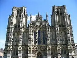 Large ornate grey stone facade of a building. Symmetrical with towers on either side.