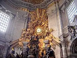 The chair-shaped bronze reliquary which holds the throne of St Peter is much larger than a normal chair, is ornate in shape and decorated with relief sculpture and gold leaf. The "Gloria" which surrounds a round window is a sculpture of clouds and sun-rays, surrounded by angels, the whole lot being covered in gleaming gold leaf.