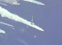 A trapezoidal gray section of the shuttle among several plumes of smoke and vapor against the blue sky