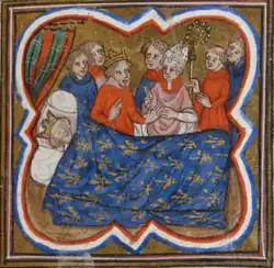 A crowned man lying on a bed covered with a blanket, with another crowned man, a bishop and other people standing neargy