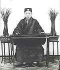 Upper Class Man Sitting at a Table Playing the Qin, 1906-1912.