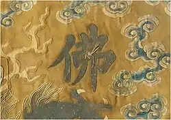 Detail of outer-most burial garment. The loose threads over the Chinese-character for Buddha ('佛') was the former position of a sewn pearl, prior to it being violently torn away.