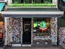 The exterior façade of the coffeeshop "Green Place" entirely covered with stickers in Amsterdam. 2024