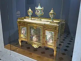 Commode of Madame du Barry; by Martin Carlin (attribution); 1772; oak base veneered with pearwood, rosewood and amaranth, soft-paste Sèvres porcelain, bronze gilt, white marble; 87 x 119&nbsp;cm; Louvre[66]