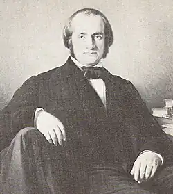 A middle-aged man, beardless, with dark hair and a receding hairline, looking straight at the camera.