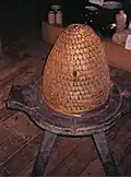A bee skep at Dalgarven Mill. The base is part of an old cheese press.