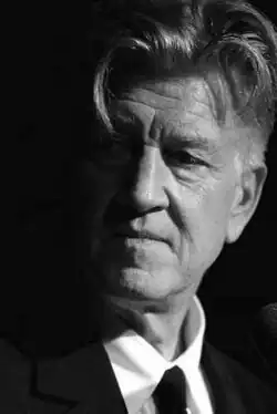 Portrait of David Lynch, a white middle-aged man, with short hair, a shaved beard, fairly aged, greyscale.