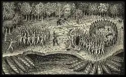 A black and white engraving. Two masses of Native North Americans face each other in the center, firing at each other with bows and arrows. In front of each group there are a number of canoes pulled up against the shore of a body of water. In the background are trees. Between the two groups stands a single man wearing some sort of armor. He is firing a rifle or musket at the group on the right, and a puff of smoke rises from the weapon. Further back near the trees are two other men who are also firing weapons at the group on the right. Two wounded individuals are lying on the ground next to the group on the right.