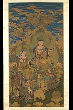 Qing dynasty (1644-1912) painting of two manifestations of Guanyin by Ding Guanpeng. 1750. The painting depicts two versions of Guanyin, each attired in silk and jewelry and holding sutras while seated in the position of “royal ease” atop elaborate pedestals. In the foreground are an arhat carrying a walking staff, the child prodigy Shancai seeking spiritual council, and a six-tusk white elephant, all paying homage to Buddhist thought.