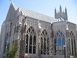 Cathedral-sized arched and intricate windows on chapel are displayed prominently in the foreground with larger soaring chapel peaking out at the top