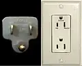 Left: NEMA&nbsp;5-15 plug. Right: "Decora"-style duplex socket, with ground-pin up orientation specified in NECA&nbsp;130-2010, center. Photos are different scale – parallel blades are on 1⁄2-inch (12.7&nbsp;mm) centers.