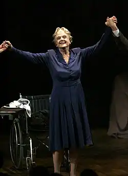An elderly woman with her arms held aloft.