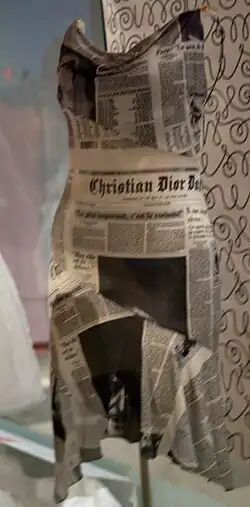 A dress made of newspaper print fabric displayed in a museum setting