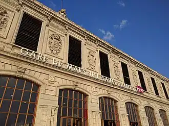 Front view of Marseille-Saint-Charles station showing its stone exterior, arched windows and engraved architectural details.