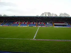 Bury F.C.'s blue stadium seated stand covered in red, white and black F.C. United banners.